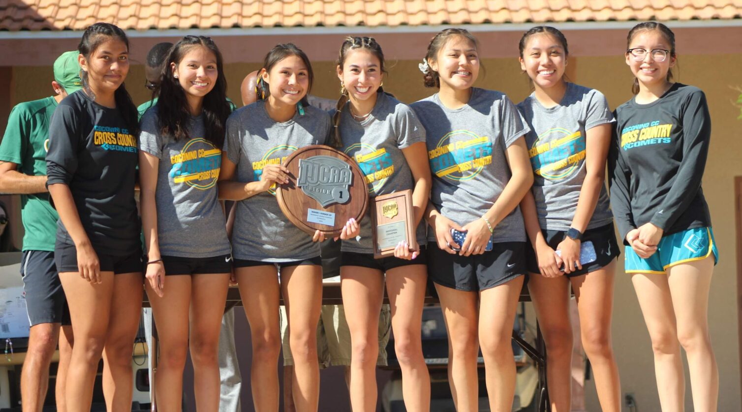 Seven female athletes pose together with a team award.