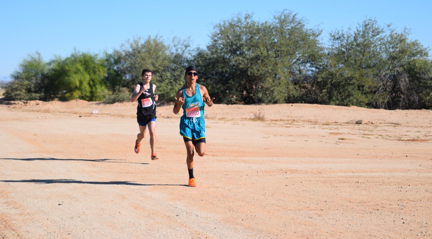 Two runners racing down a dirt road.