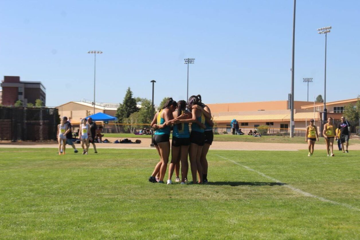 CCC's women's cross country team huddles up with their arms around each other.