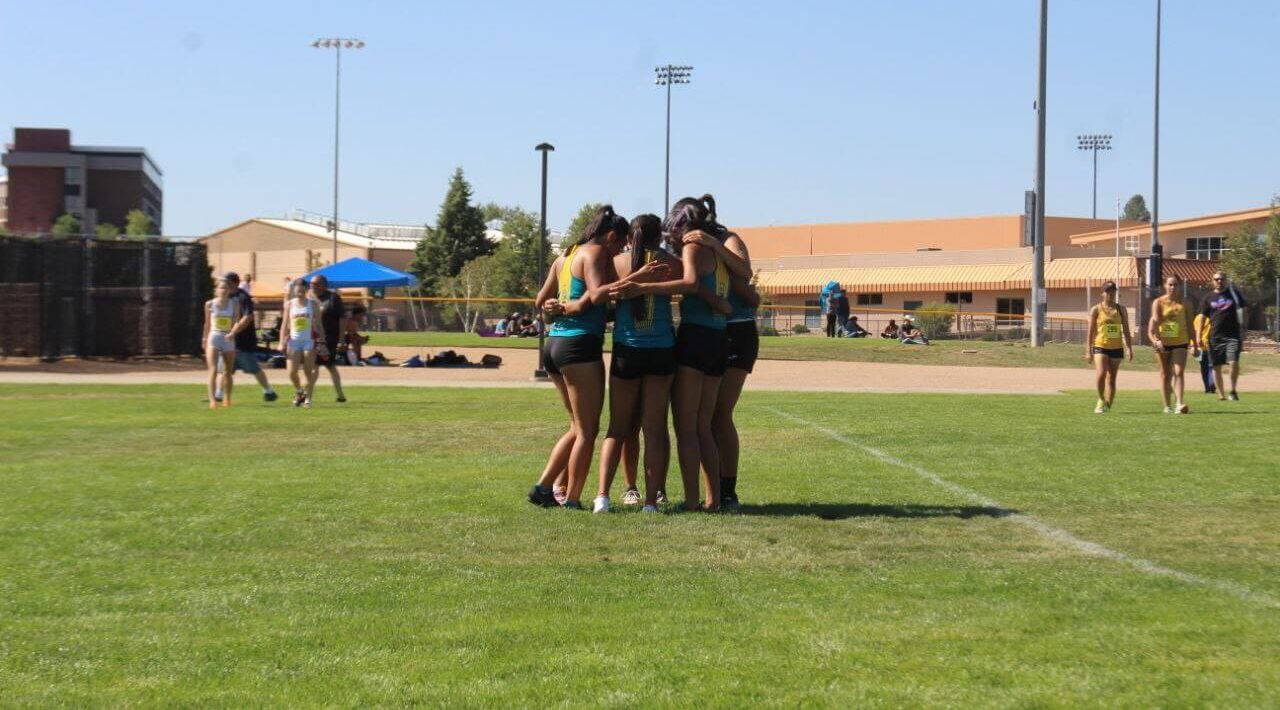 CCC's women's cross country team huddles up with their arms around each other.