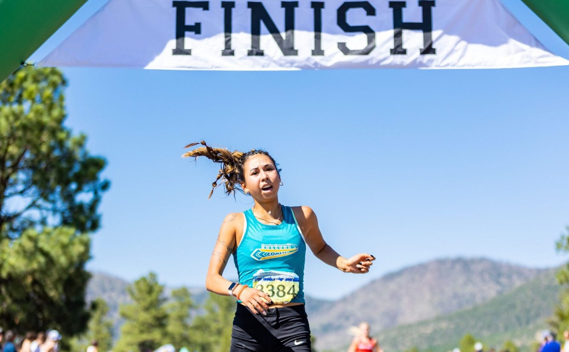 A female athlete crossing the finish line of a cross country race.