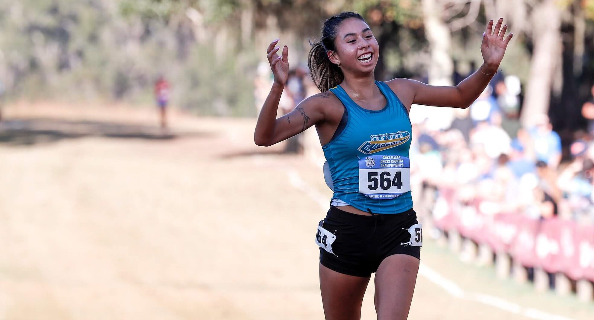 Coconino Community Colleges Hayley Burns with her hands up as she wins the 2022 Cross Country National Championships.