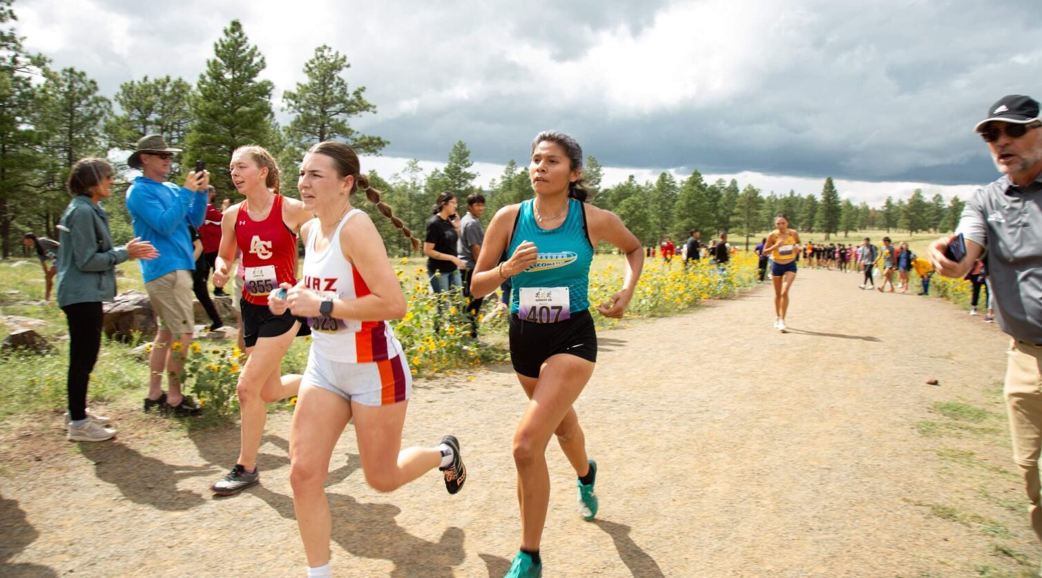 Three female runners race each other down a dirt path.