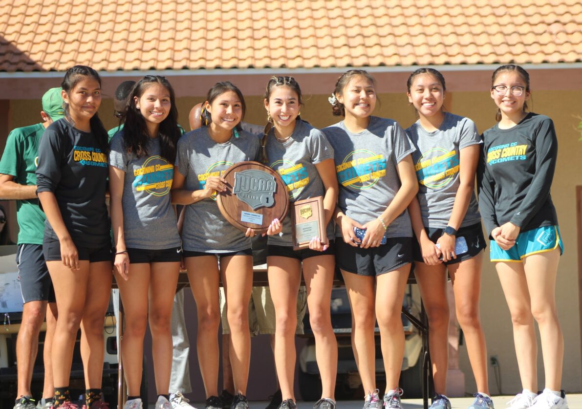 2022 Women's Cross Country posing as a team with a trophy.