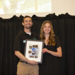 Coach Hunt posing with Julia Clarke while she holds her graduation gift.