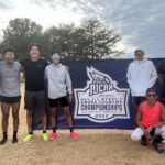 CCC's men's cross country team posing in front of a National Championship banner.