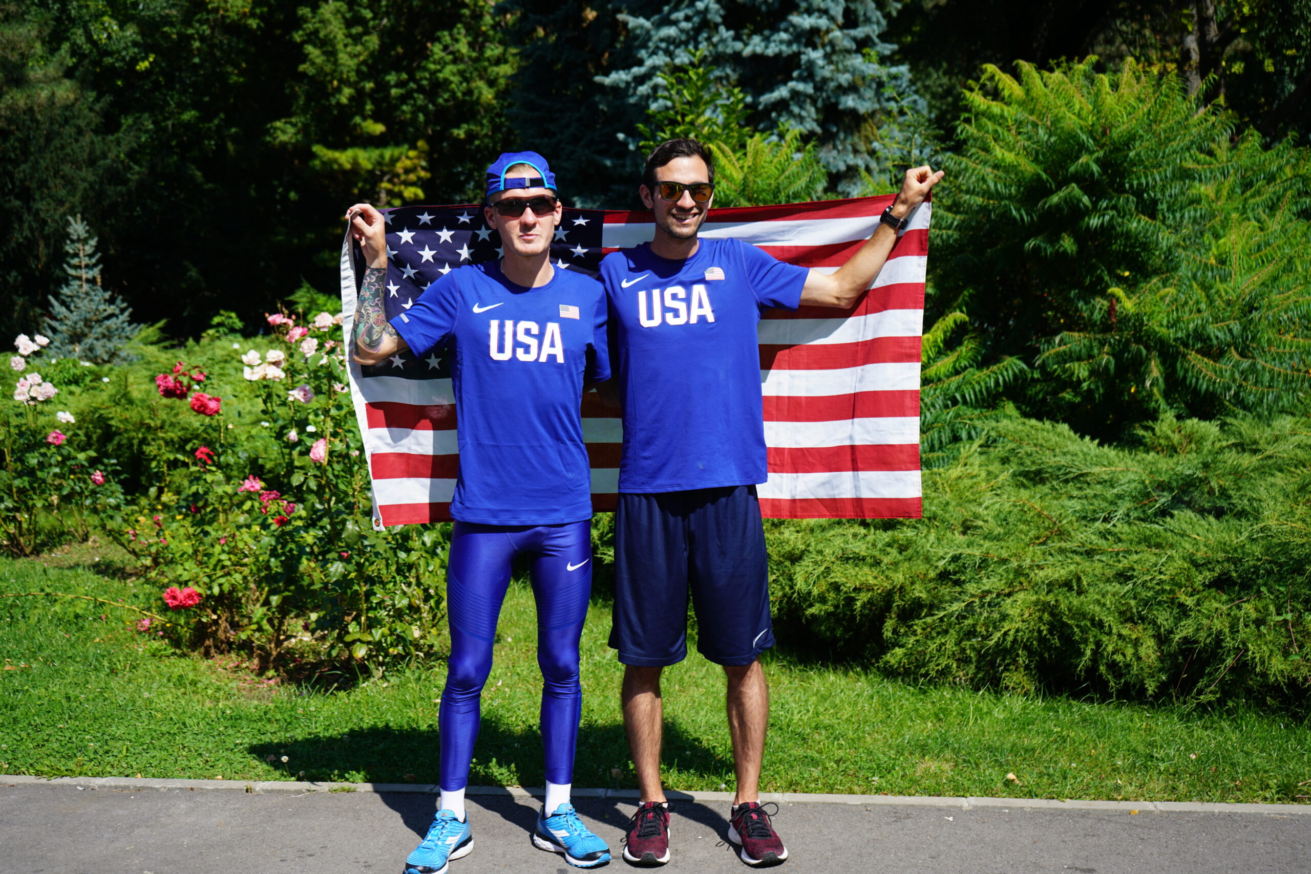 Two male athletes standing holding an American flag.