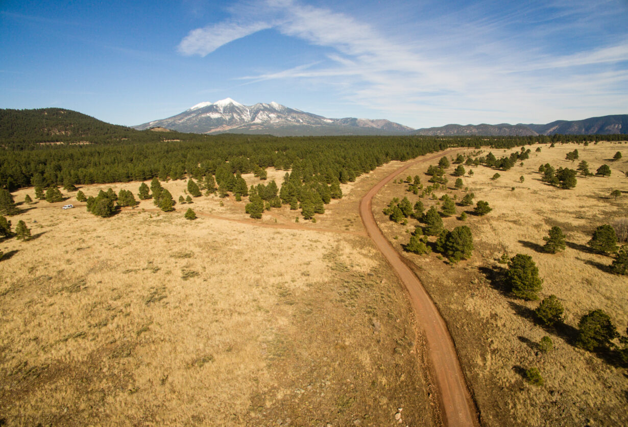 Drone photo of a long dirt road leading into the mountains.