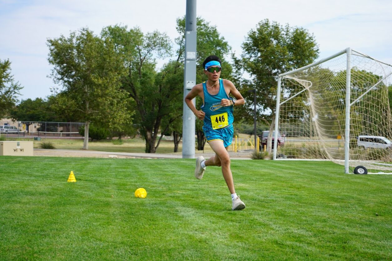 Zach Biah, of coconino community college runs over a grassy field during a cross country race.