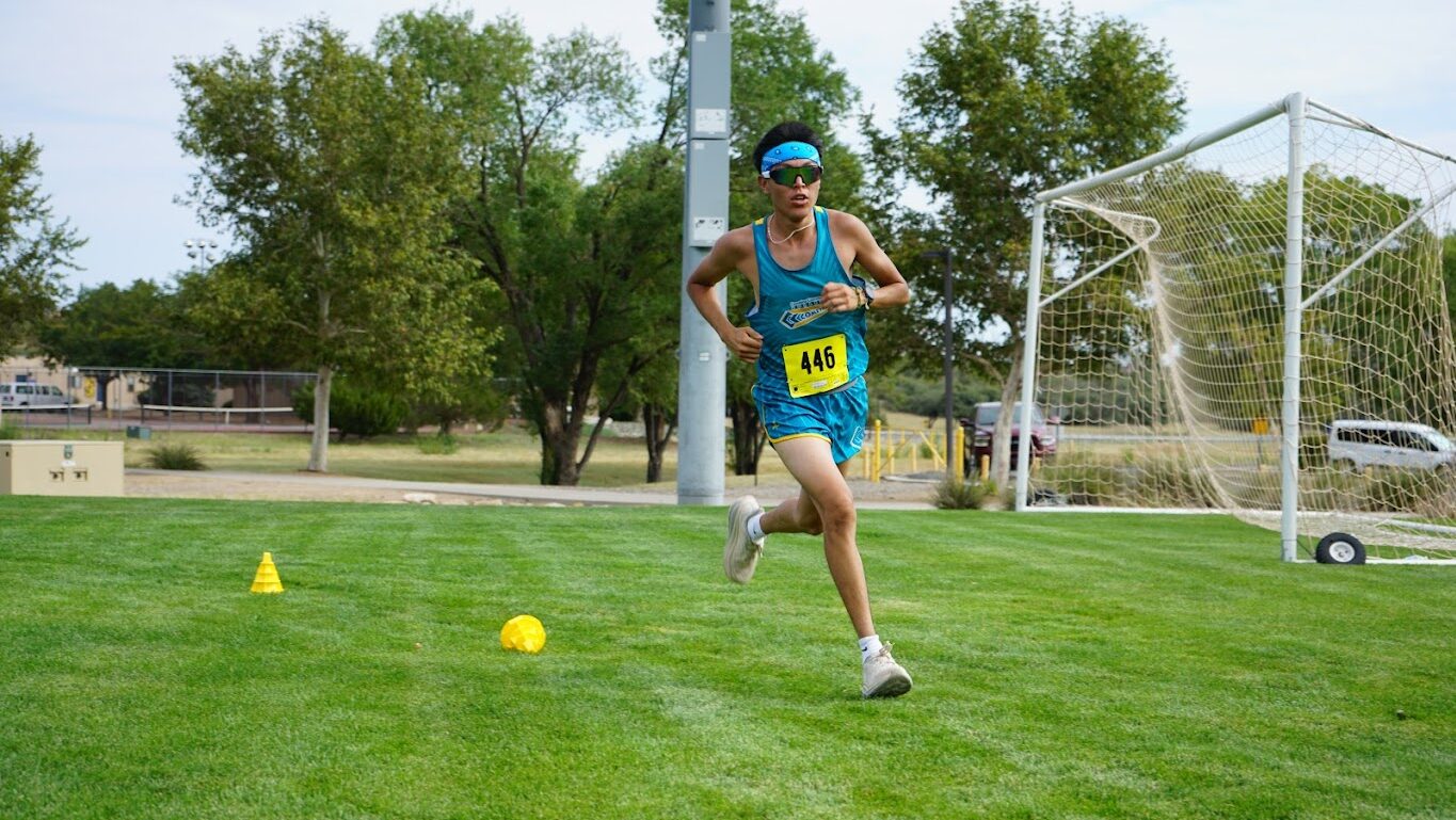 Zach Biah, of coconino community college runs over a grassy field during a cross country race.