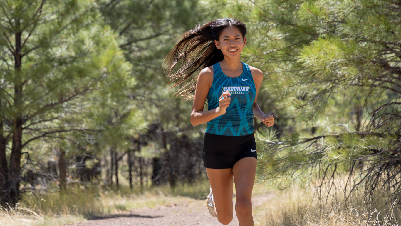 female runner from CCC runs down a dirt path.