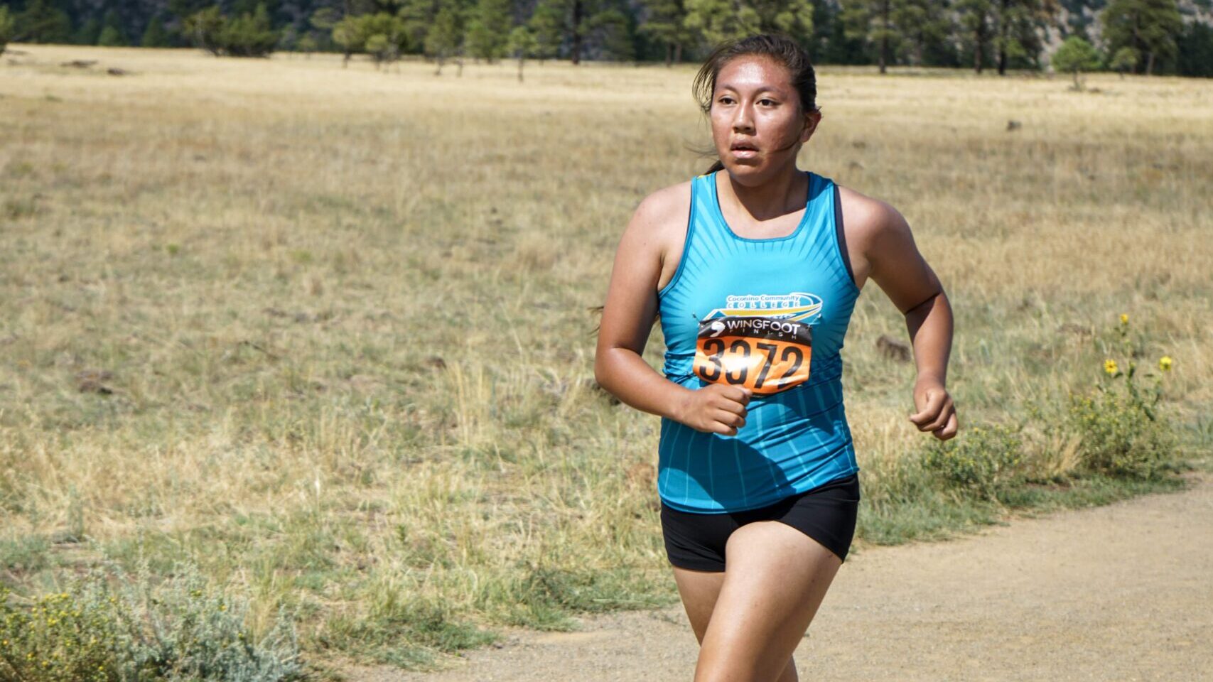 CCC cross country runner racing down a dirt path.