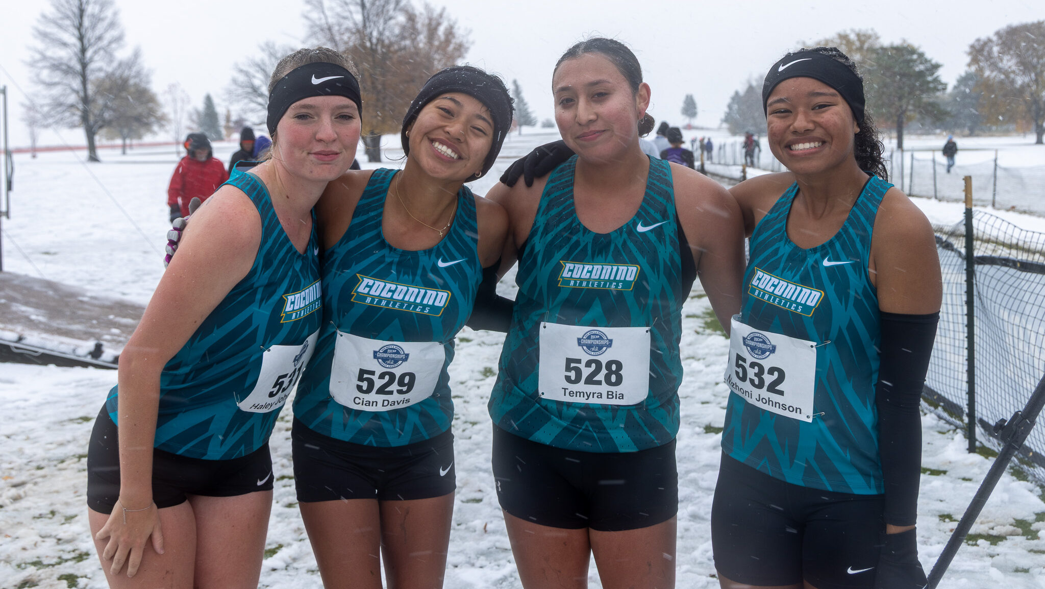 Four cross country runners pose for a picture after their race in the snow.